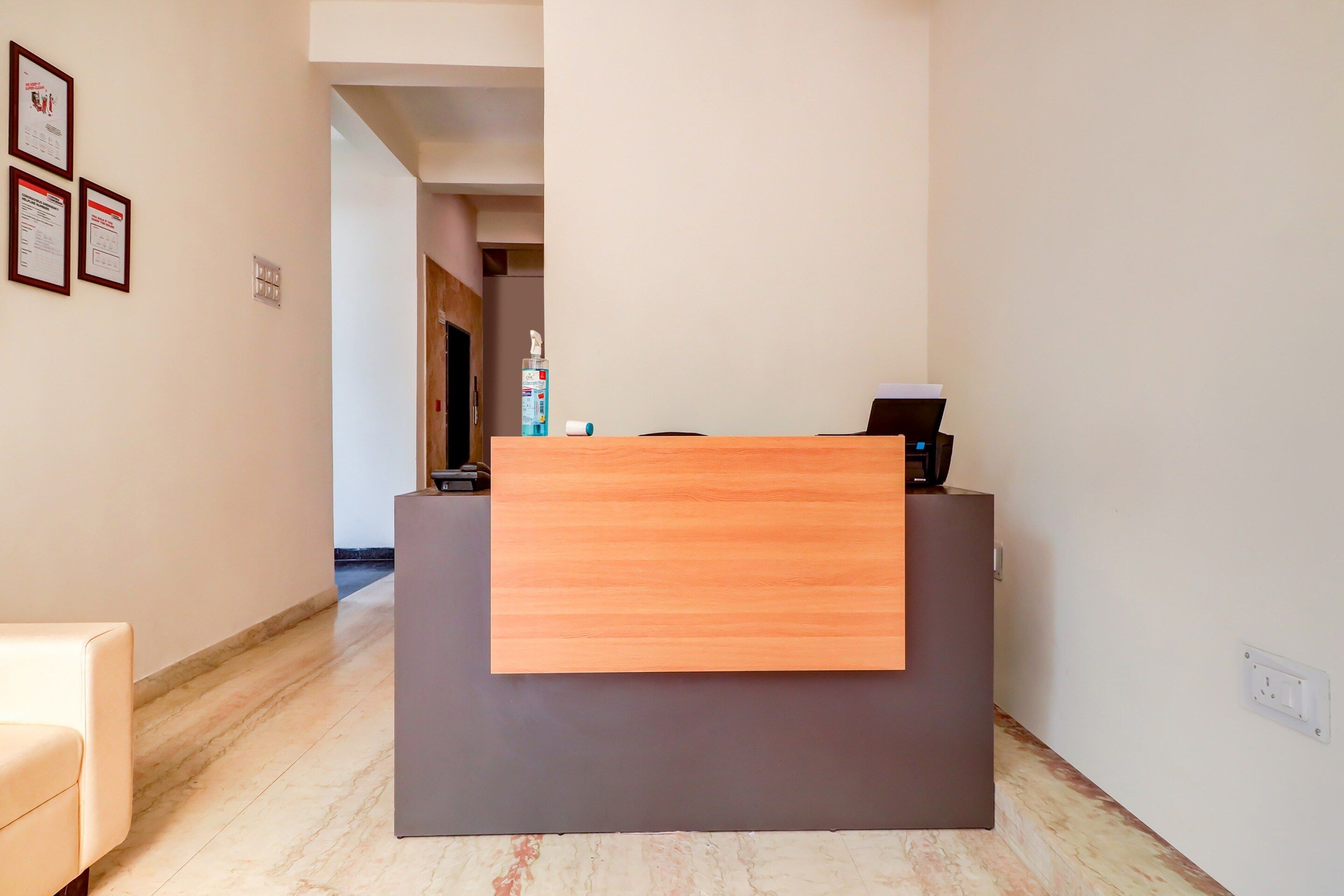 A reception desk with a wooden panel, a bottle of hand sanitizer, and a black object on top, likely a phone or a small device.