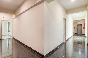 A clean, modern hallway with a shiny floor, a door with a mirror, and an elevator. - Hotel O Hotel Outline (Ranchi)