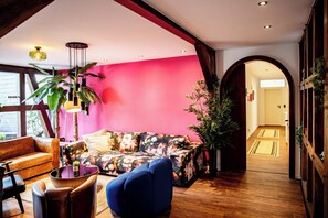 A modern living room with a vibrant pink wall, a wooden floor, and a blue armchair. - GoodTimes, 189 m², sauna, large balcony, and right in the heart of Winterberg (Winterberg)