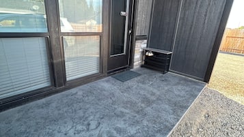 A modern building entrance with a concrete floor, a door, and a small step leading to a gravel area.