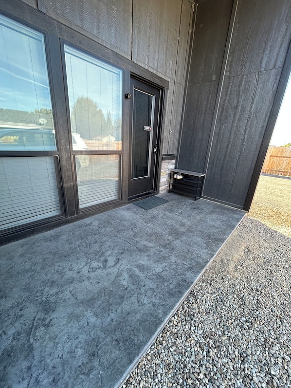 A modern building entrance with a concrete floor, a door, and a small step leading to a gravel area.