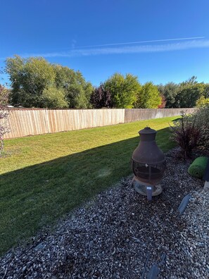 A backyard with a wooden fence, a metal outdoor heater, and a well-maintained lawn.