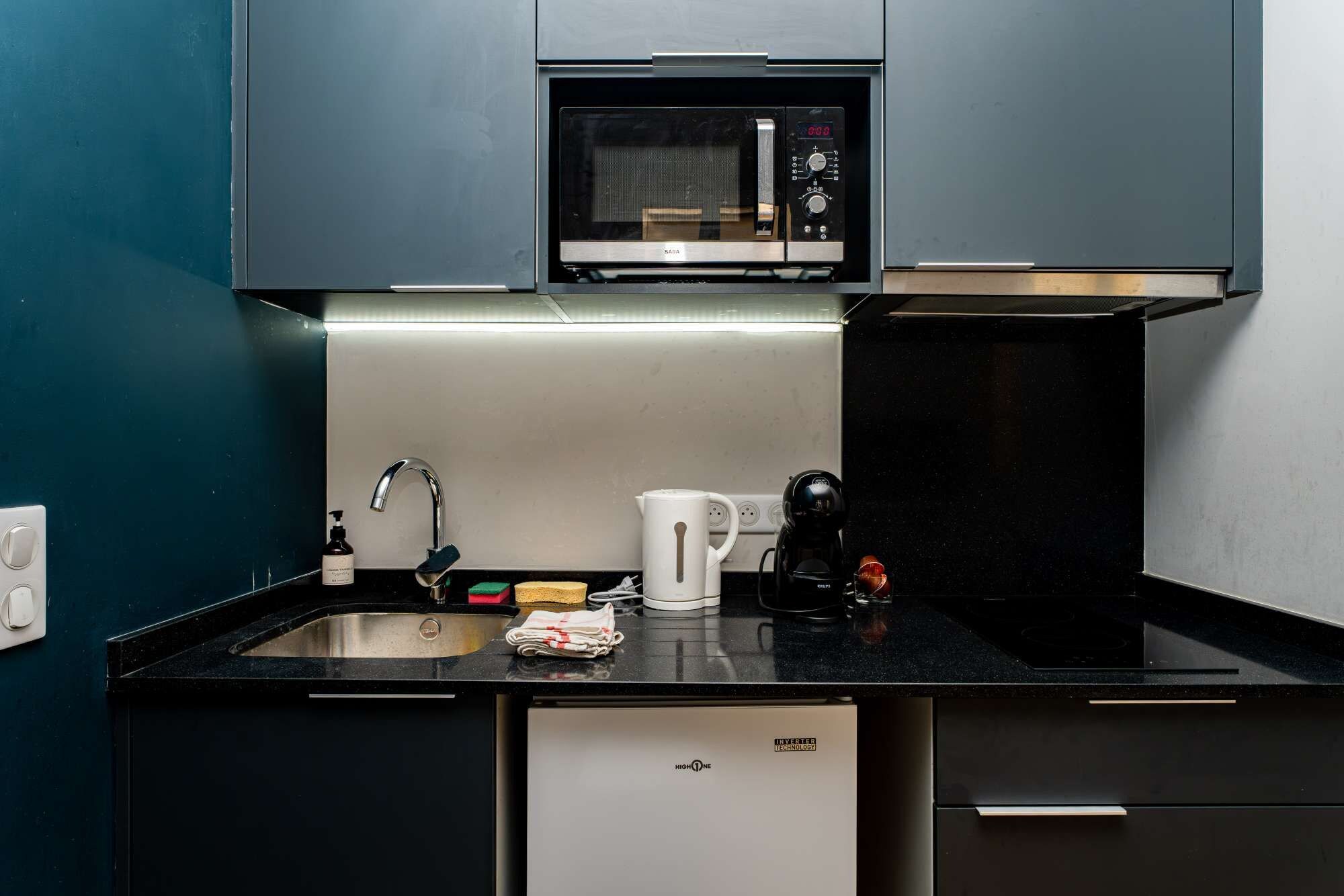 A compact kitchen with a microwave, sink, and a coffee maker.
