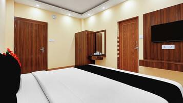 Habitación de hotel con cama, armario de madera, espejo, televisión y un pequeño baño.