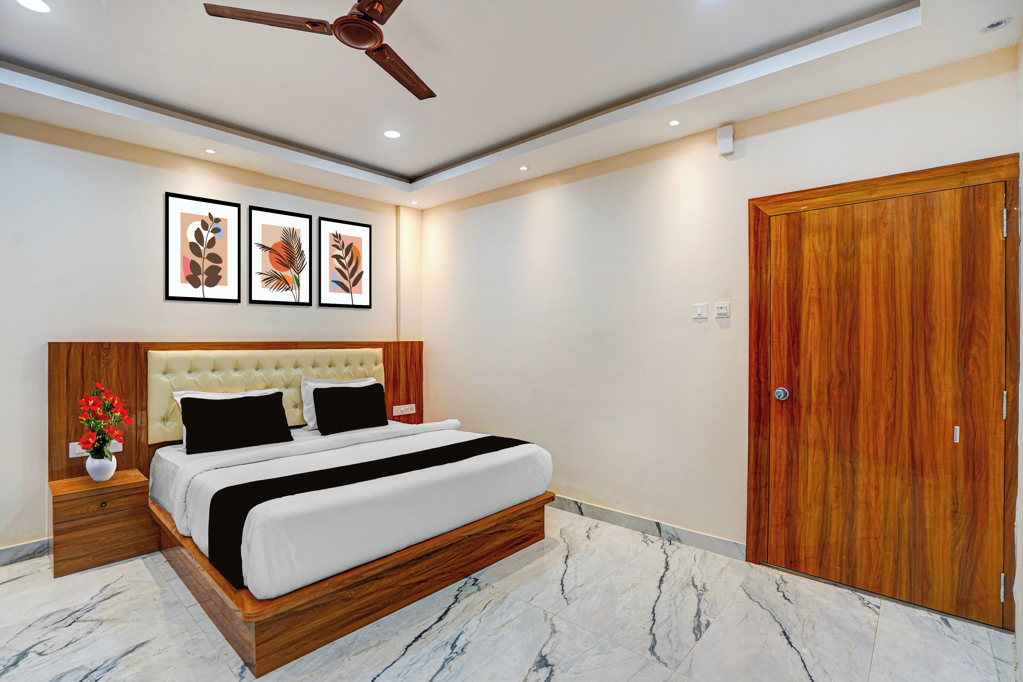 Habitación de hotel con cama, cabecera de madera, ventilador de techo, armario de madera y piso de mármol.