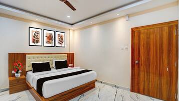 Habitación de hotel con cama, cabecera de madera, ventilador de techo, armario de madera y piso de mármol.