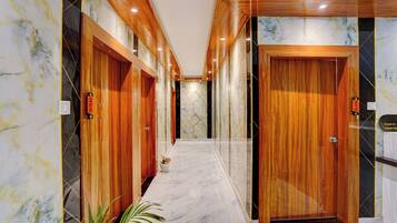 Un pasillo de hotel con puertas de madera, paredes de mármol y una planta en maceta.