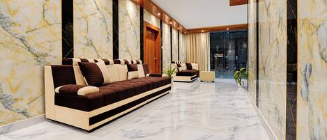 Un interior moderno con piso de mármol, un sofá largo y techo de madera.