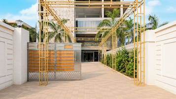 Una entrada protegida por un portón metálico y una valla de madera, que conduce a un edificio de estilo arquitectónico moderno.