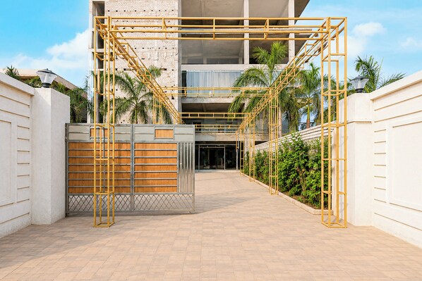 A gated entrance with a metal gate and a wooden fence, leading to a building with a modern architectural style.