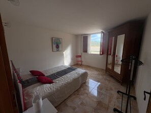 Ein Schlafzimmer mit einem Bett, einem Stuhl, einem Fenster und einem Kleiderschrank.