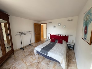 A bedroom with a bed, a wardrobe, a mirror, a door, and a wall-mounted light fixture. - Holiday home 'Gîte Les Piboules' with Mountain View, Wi-Fi and Air Conditioning (Caseneuve)