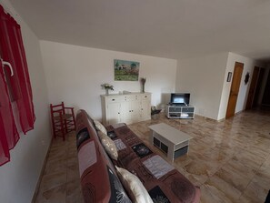 Een woonkamer met een bank, een tv-meubel en een schilderij aan de muur.