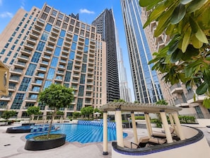 A modern high-rise building with a swimming pool and outdoor seating area. - FIRST CLASS | 1BR | Elegant Dubai Skyline (Downtown)