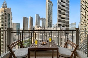 A balcony with a table and chairs, overlooking a cityscape with modern buildings. - FIRST CLASS | 1BR | Elegant Dubai Skyline (Downtown)