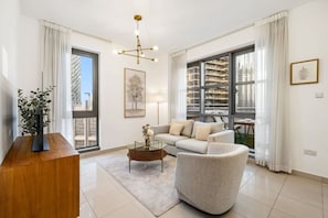 A modern living room with a sofa, a coffee table, and a plant. - FIRST CLASS | 1BR | Luxe Burj & City View (Downtown)