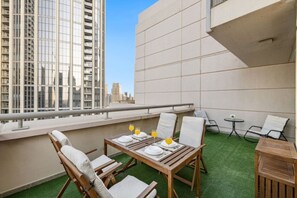 A rooftop terrace with a dining table set for two, surrounded by chairs, and a small round table with a chair. - FIRST CLASS | 1BR | Luxe Burj & City View (Downtown)