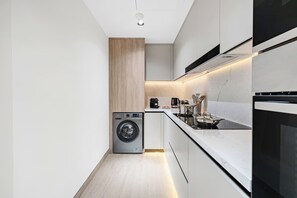 A modern kitchen with a built-in washer, a stove, and a coffee maker. - FIRST CLASS | 3BR | Near JBR Beach | Ain Views (JBR)