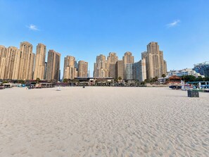 A sandy beach with high-rise buildings in the background. - FIRST CLASS | 3BR | Near JBR Beach | Ain Views (JBR)
