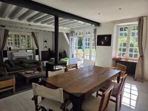 A cozy living room with a fireplace, a dining table, and a sofa. - Just an hour from Paris, a spacious home perfect for family gatherings (or working from home)...   (Guainville)