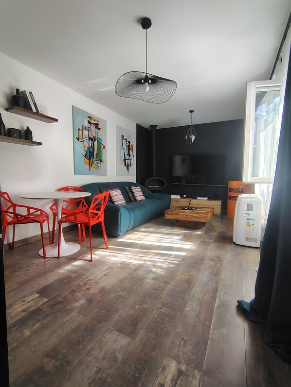 A modern living space with a sofa, dining table, and chairs, a flat-screen TV, and artwork on the walls.