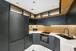 A modern kitchen with built-in appliances, a corner sink, and a wooden accent wall. - FIRST CLASS | 2BR | High Floor | Stunning Sea View (Marina)