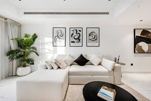 A modern living room with a white sofa, a black coffee table, and a large potted plant. - FIRST CLASS | 2BR | High Floor | Stunning Sea View (Marina)