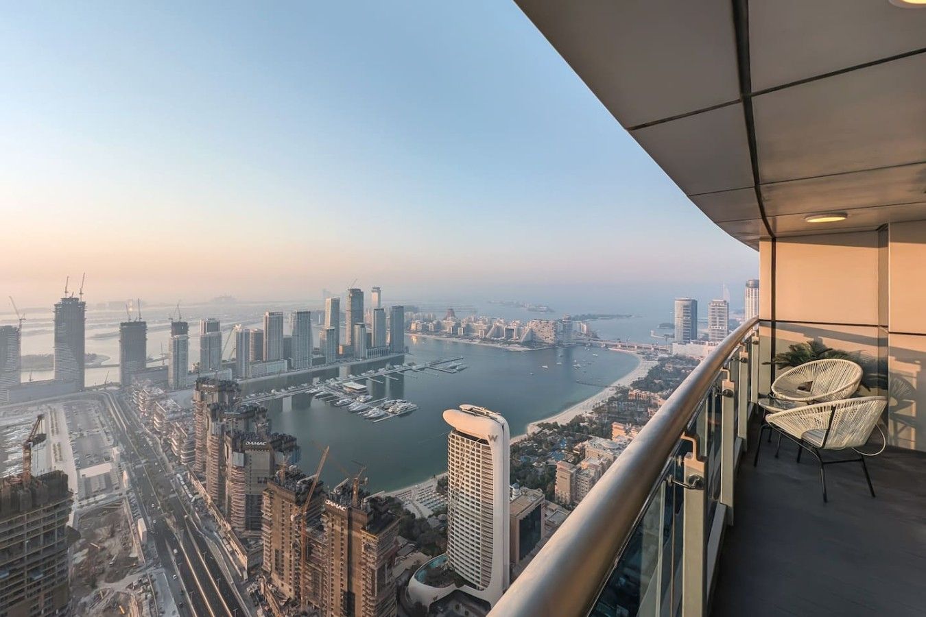 A high-rise building with a view of a marina and cityscape.