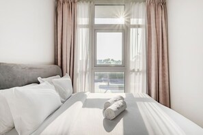 A hotel room with a bed, a window with curtains, and a view of the outside. - FIRST CLASS | Bright Luxury VILLA | Amazonia (Damac Hills)