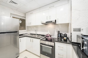 A modern kitchen with stainless steel appliances, white cabinetry, and a black countertop.