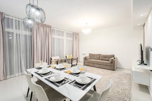 A modern dining area with a table set for four, a sofa, and a television in a living space.