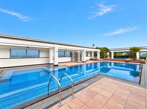 A swimming pool with a clear blue water surface, surrounded by a tiled deck area. - FIRST CLASS | 1BR | Elevated Luxury | City Views (DIFC)