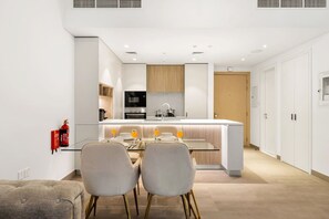 Eine moderne Küche mit einer zentralen Kochinsel, einem Essbereich mit zwei Stühlen und einem an der Wand befestigten Feuerlöscher.