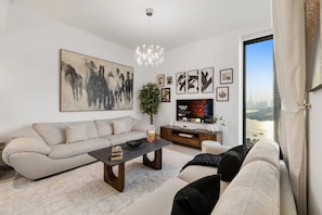 A modern living room with a sofa, coffee table, and a television. - FIRST CLASS | 1BR| Panoramic Creek Views (Dubai Creek Harbour)