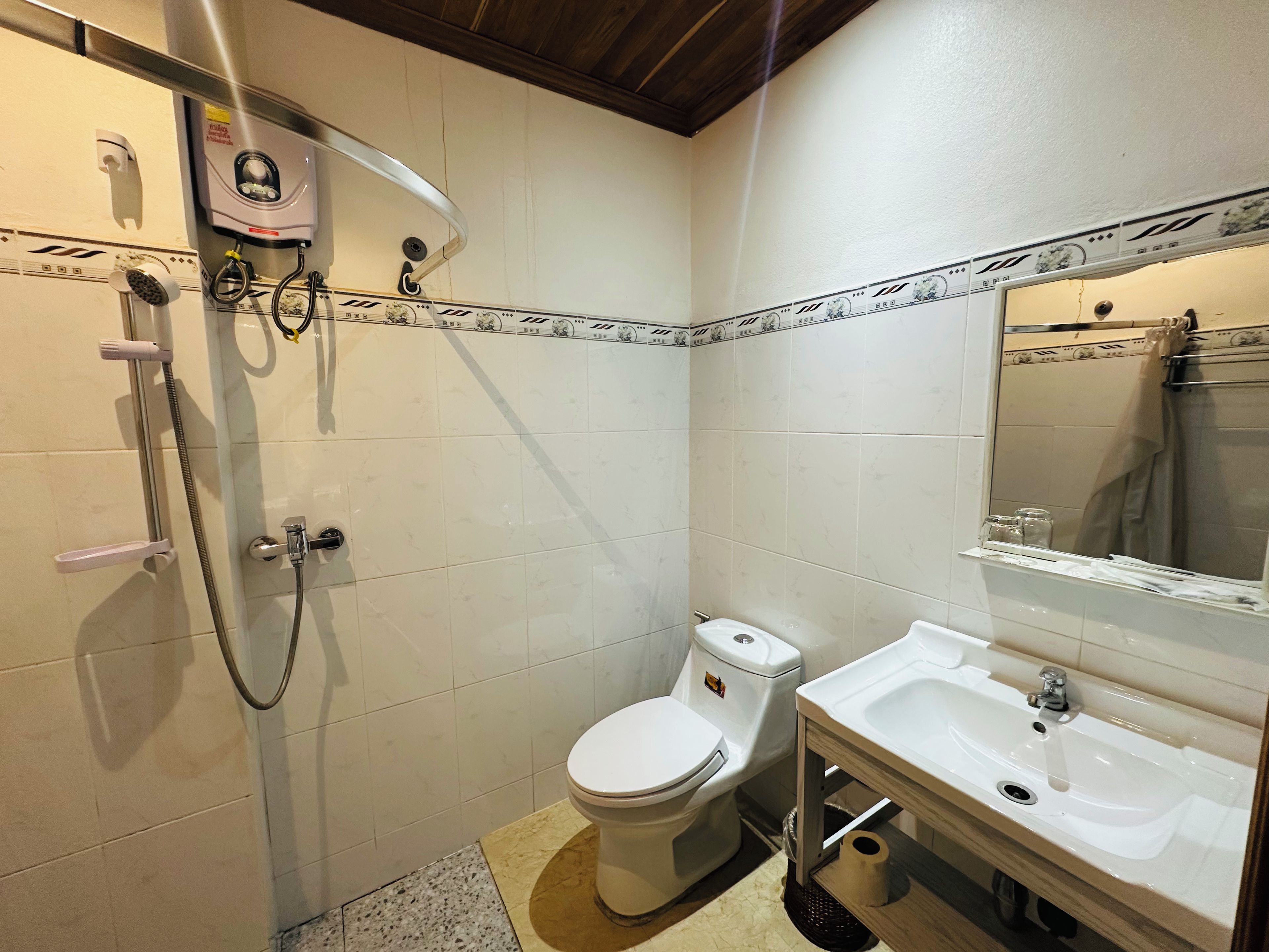 A bathroom with a toilet, sink, shower, and a towel rack.