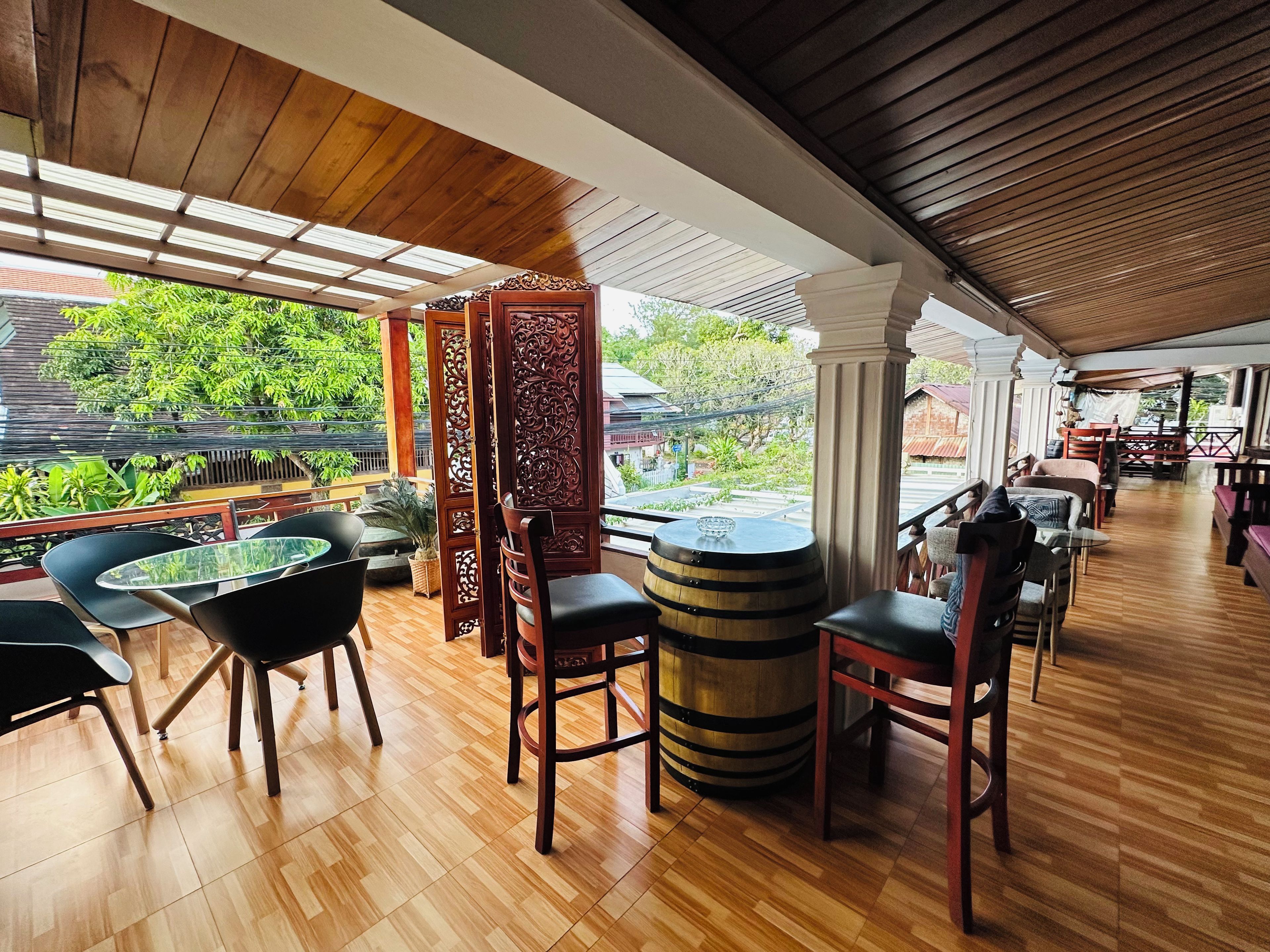 An indoor seating area with wooden flooring, tables, chairs, and a decorative wooden partition.