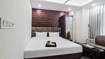Habitación de hotel con una cama grande, una mesita de noche con control remoto, una silla y un ventilador de techo.