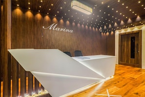 Un mostrador de recepción de diseño moderno, una pared de madera con líneas verticales e iluminación empotrada en el techo.