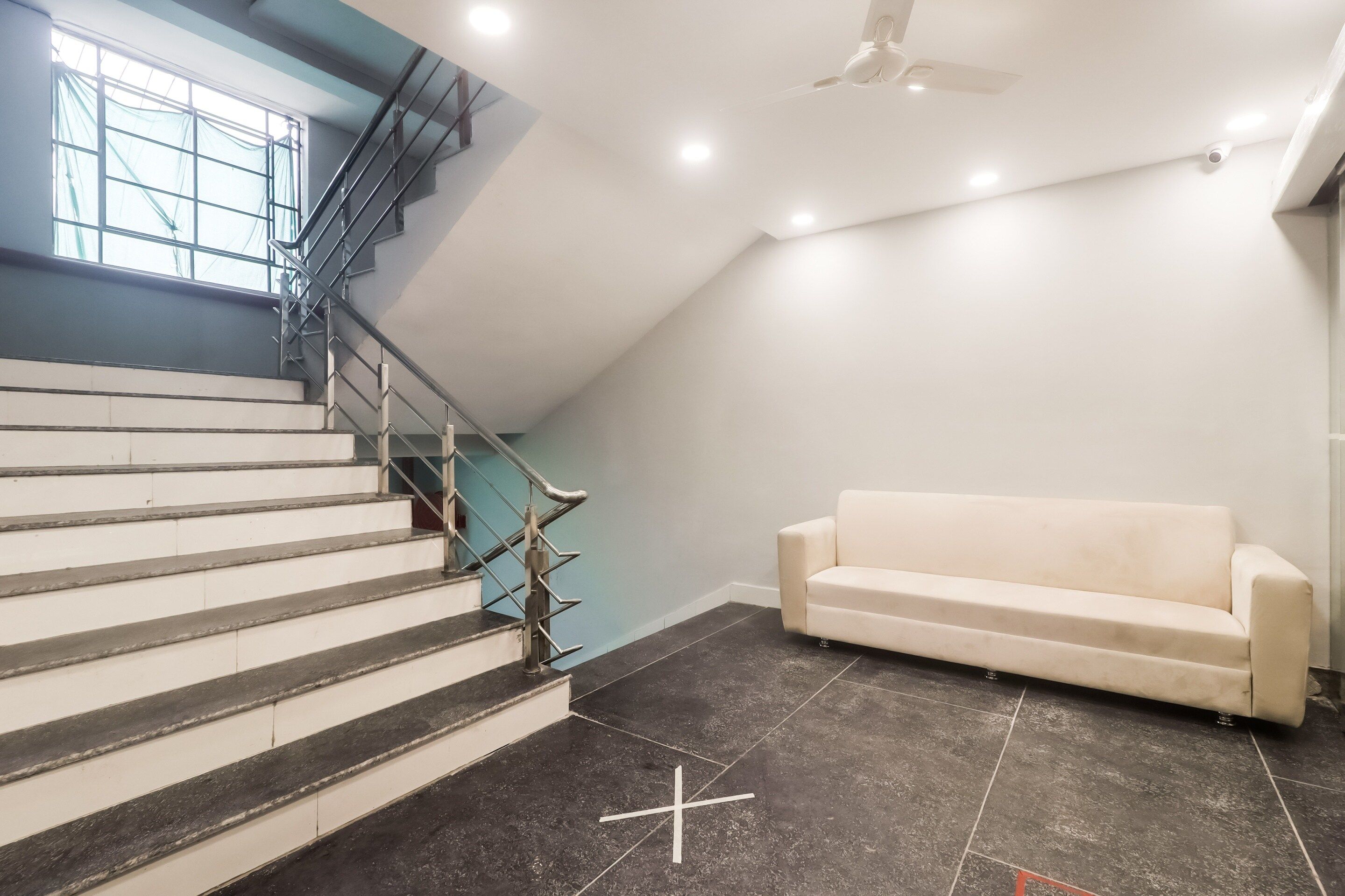 A staircase with metal railings leading to a landing, a white sofa, and a ceiling fan.