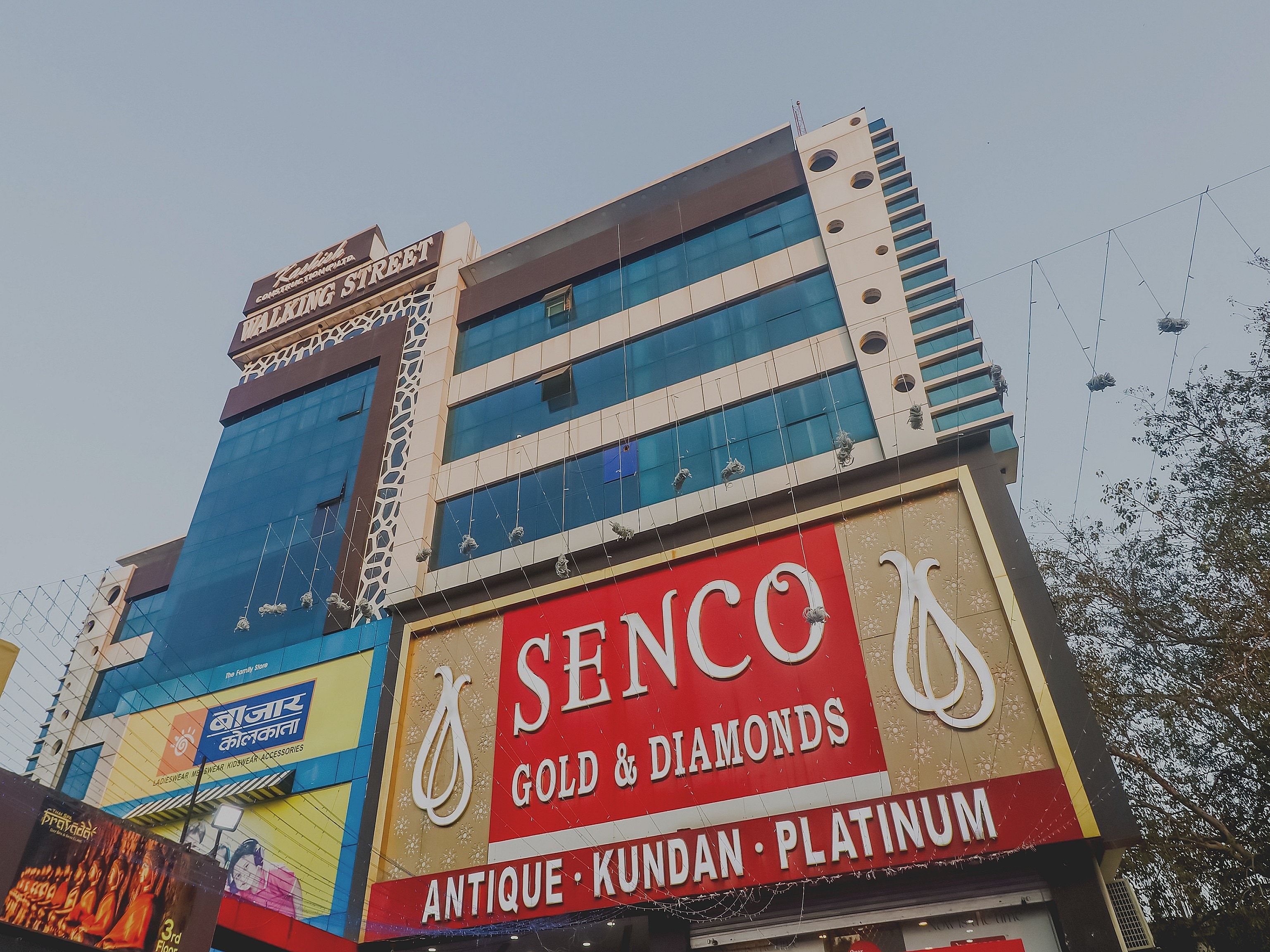 Un edificio de varios pisos con un letrero destacado de 'Senco Gold & Diamonds' y otro de 'The Family Store'.