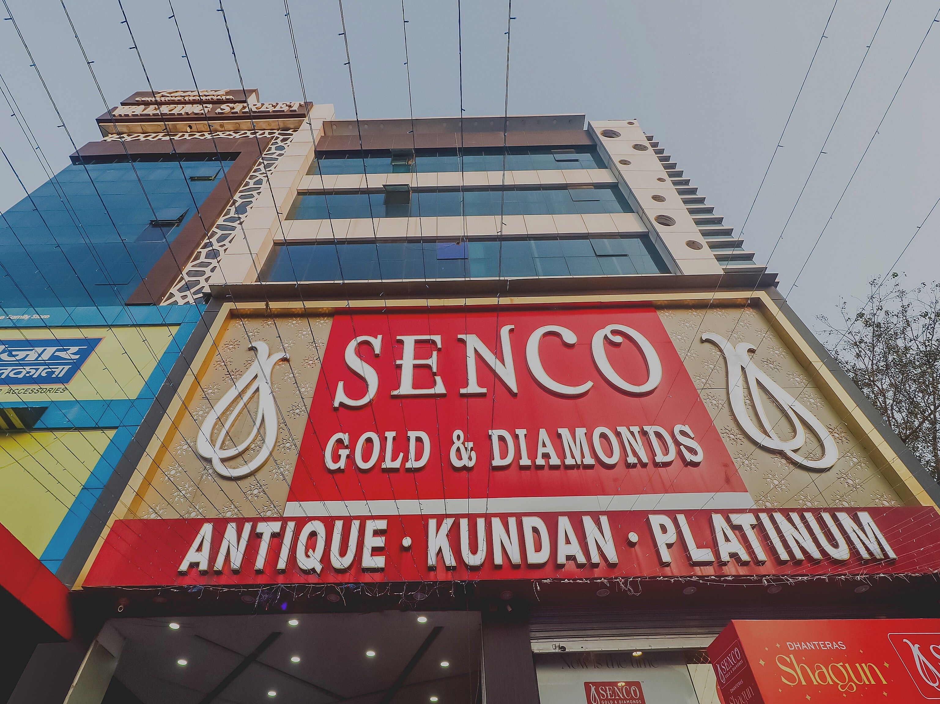 A building with a prominent sign for 'Senco Gold & Diamonds' and 'Antique, Kundan, Platinum' indicating a jewelry store.