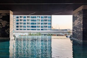 Une piscine intérieure donnant sur un bâtiment moderne à plusieurs étages et doté de nombreuses fenêtres.