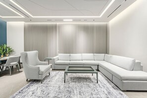Ein modernes Wohnzimmer mit einer Eckcouch, einem Couchtisch und einem Essbereich mit Stühlen und einem kleinen Tisch.