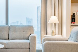 A hotel room with a sofa, a side table with a lamp, and a minibar. - FIRST CLASS | 2BR | Prime Downtown | City Views (Downtown)