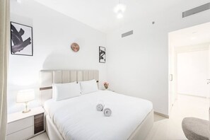 A hotel room with a bed, bedside tables, a clock, and artwork on the walls. - FIRST CLASS | 2BR | Prime Downtown | City Views (Downtown)
