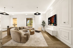 A modern living room with a sectional sofa, a coffee table, and a flat-screen TV mounted on the wall. - FIRST CLASS |4BR| Vibrant Retreat Near JBR Beach (JBR)
