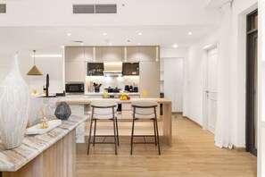 A modern kitchen with a central island, bar stools, and a dining area. - FIRST CLASS |4BR| Vibrant Retreat Near JBR Beach (JBR)