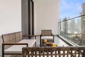 Ein Balkon mit Korbmöbeln, einem Glastisch und einem Frühstücksarrangement.