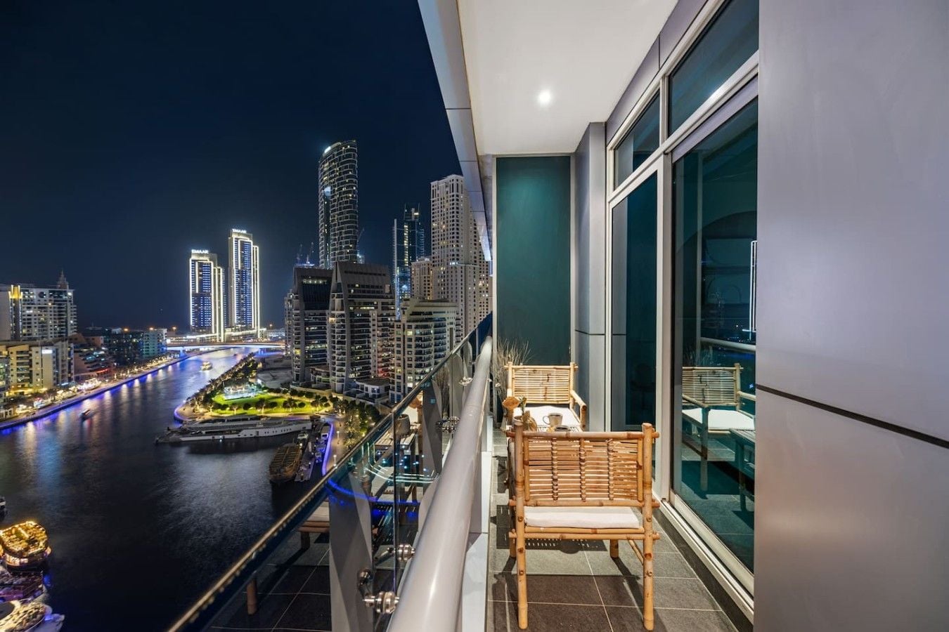 A balcony with a view of a city skyline at night, a chair, and a railing.