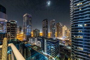 Ein nächtliches Stadtbild mit hohen Gebäuden, einem Poolbereich und wolkenlosem Himmel.